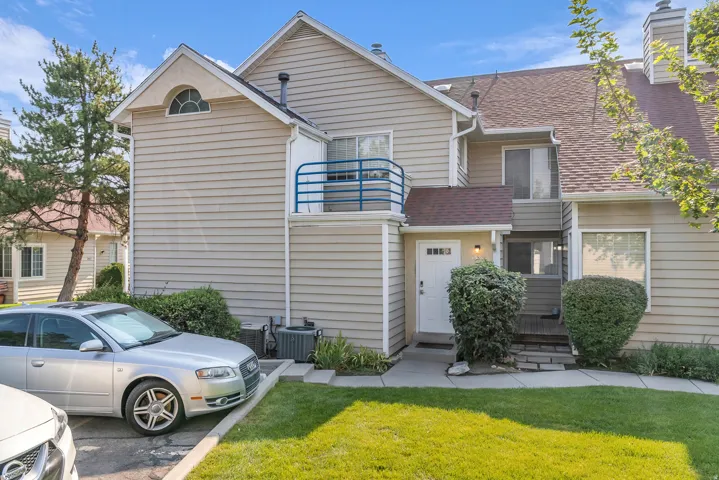 Horizontal siding exterior with a pitched shingle roof, arched window accent, and a balcony with blue railing