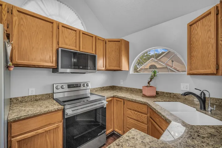 Wood-finish cabinetry paired with speckled stone countertops and a stainless steel appliance suite