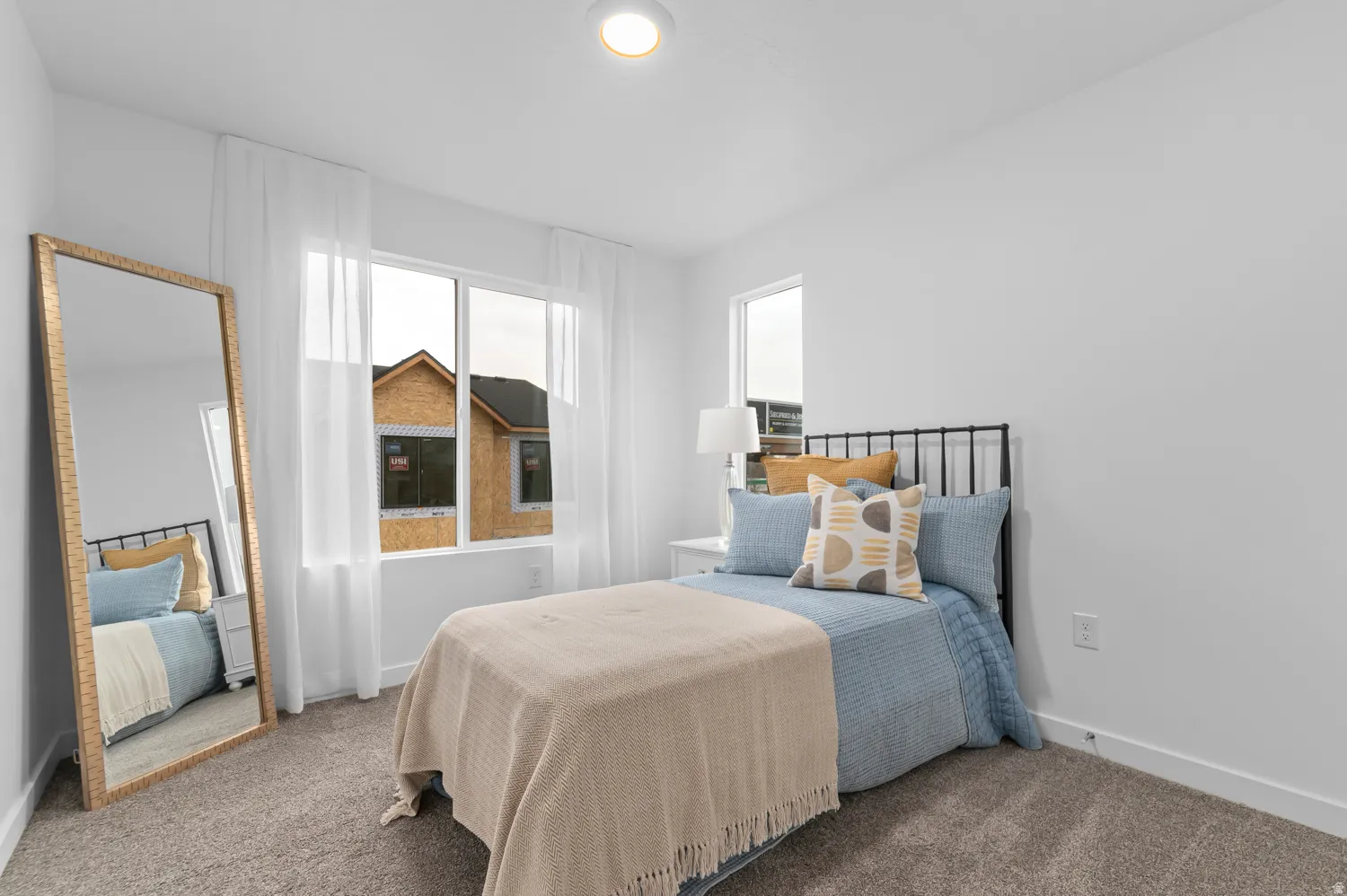 Carpeted room featuring white walls, a large window with sheer white curtains, and a recessed ceiling light