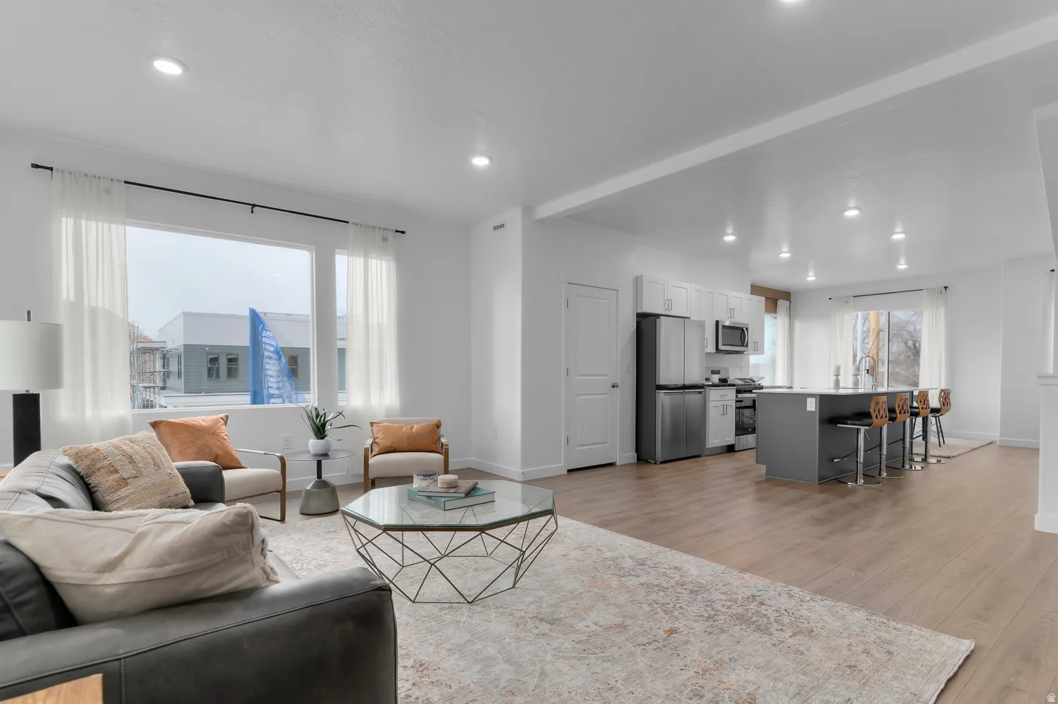 Open-concept living space featuring wood-finish flooring, recessed lighting, and a large window