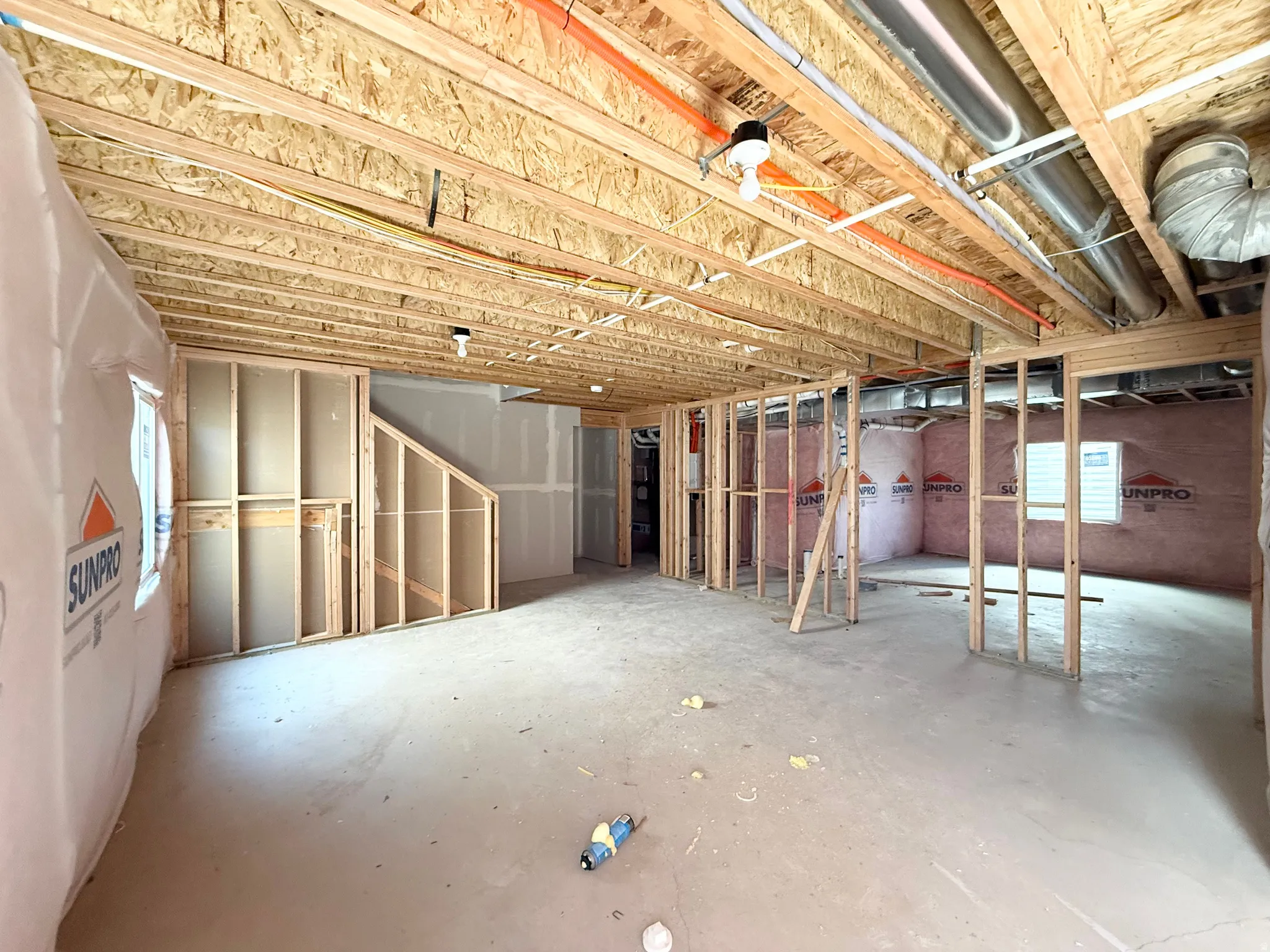 Unfinished lower level featuring exposed wood framing, concrete flooring, and visible utility lines