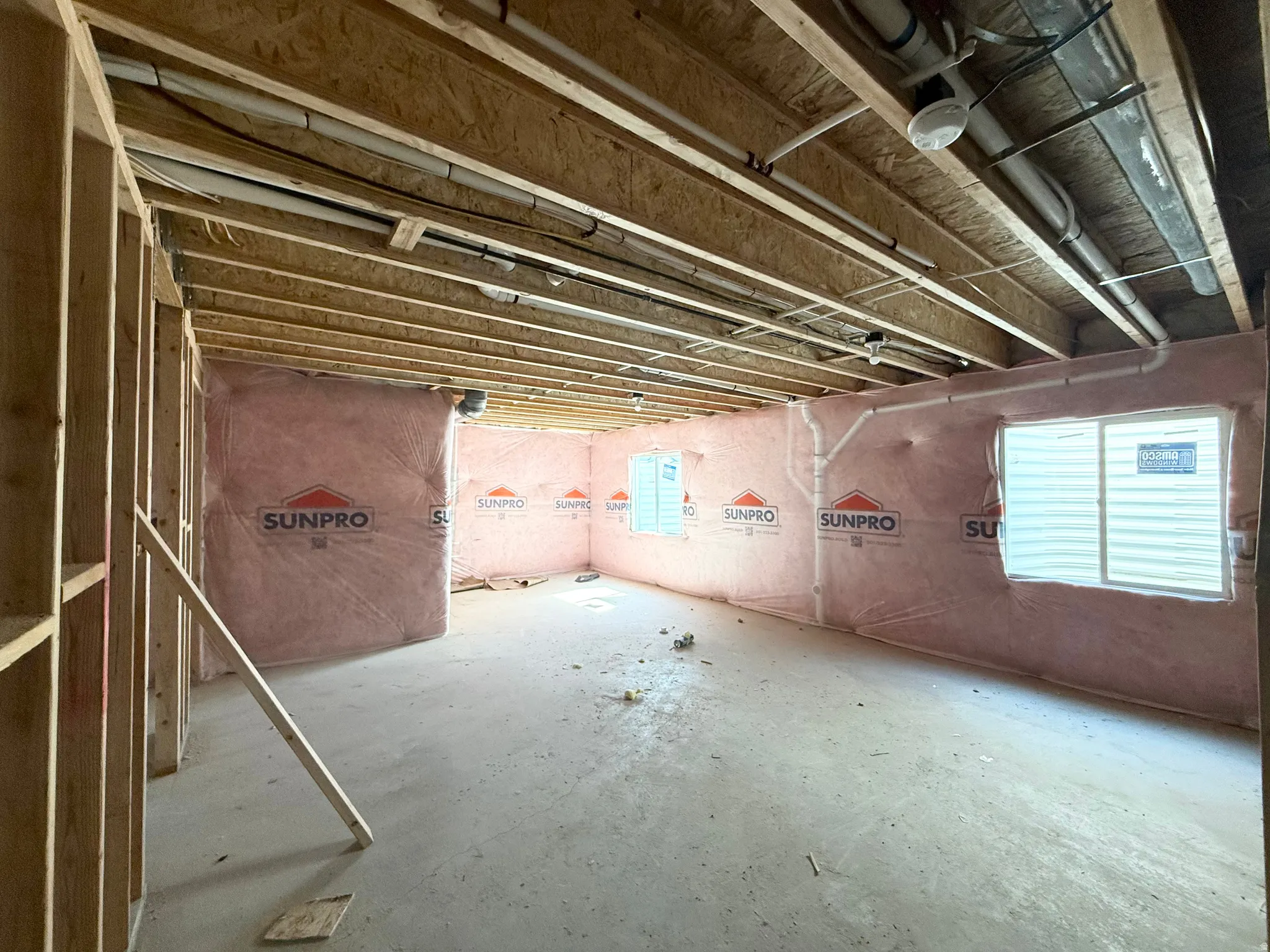 Unfinished lower level with wood framing, exposed joists, concrete flooring, and insulated exterior walls
