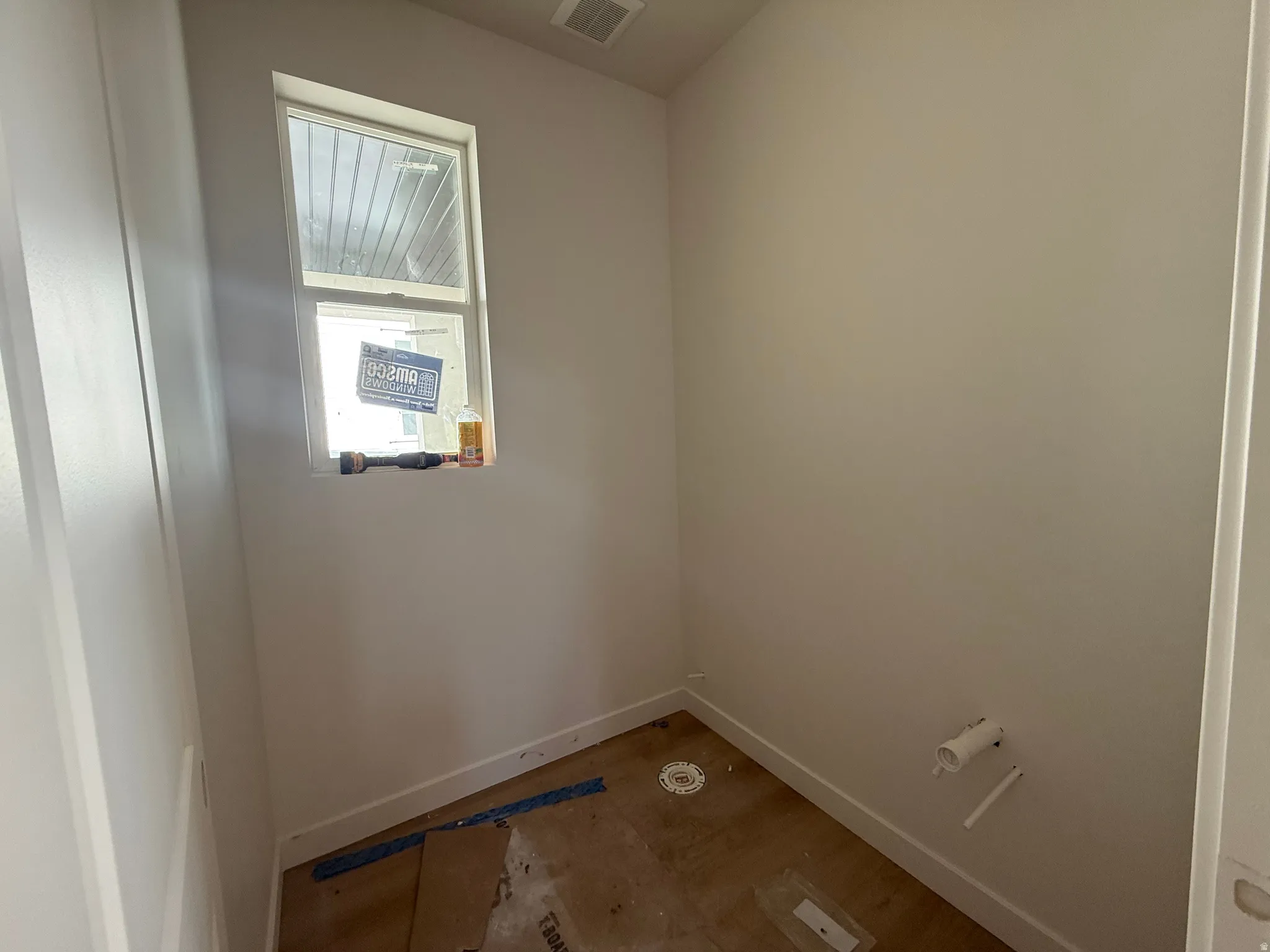 Single window, light-colored walls, white trim, wood-finish subfloor