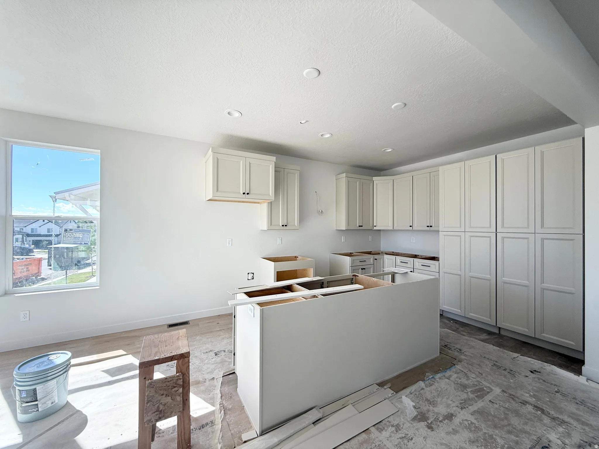 Kitchen area featuring recessed ceiling lighting, light-toned cabinetry, a window, and an island structure