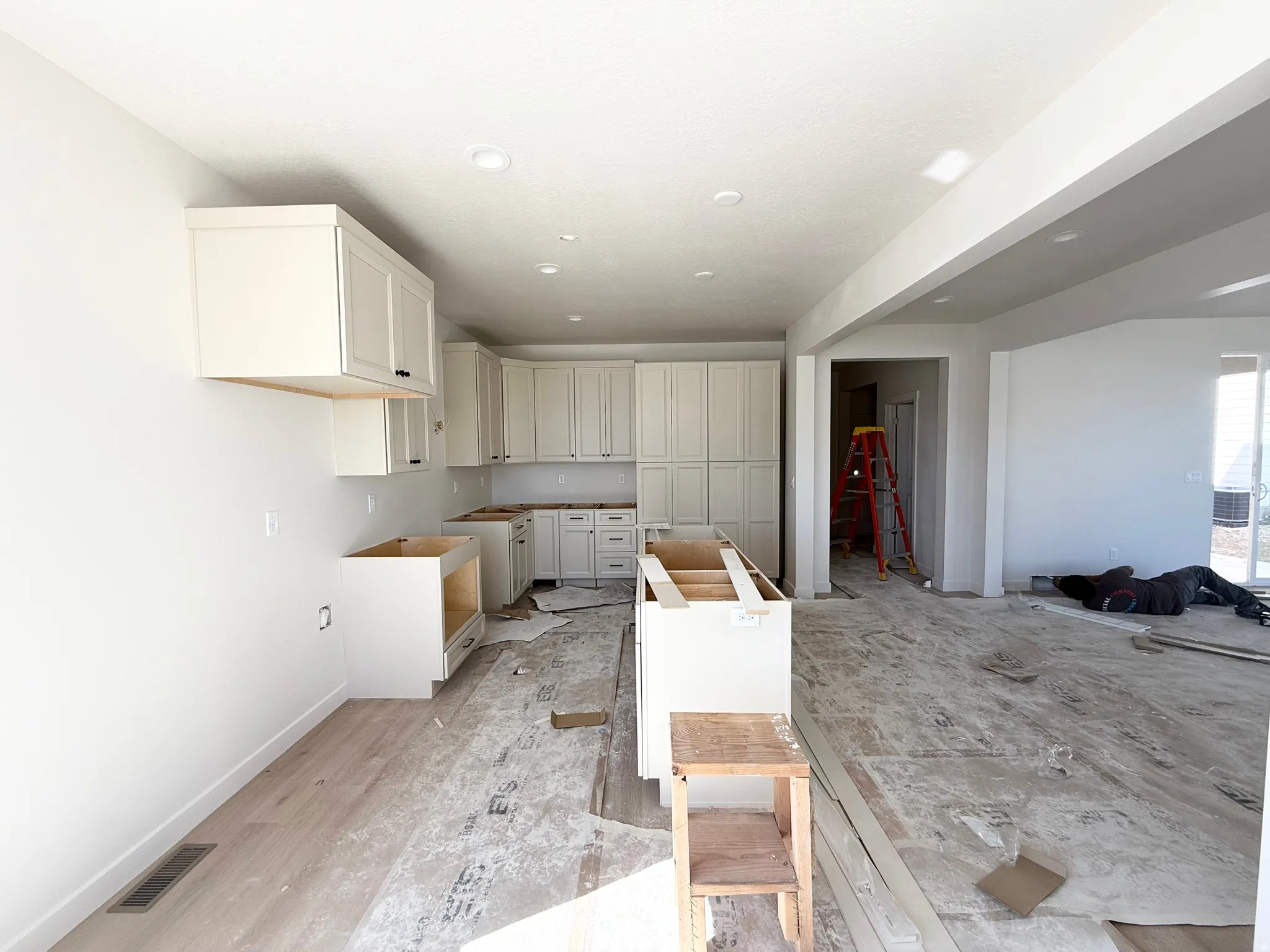 Recessed lighting, wood-finish flooring, white shaker-style cabinetry, and an open concept layout
