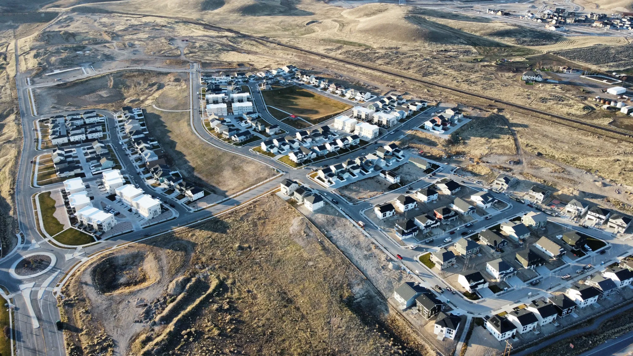 Expansive residential development featuring modern homes, paved roadways, and integrated roundabout