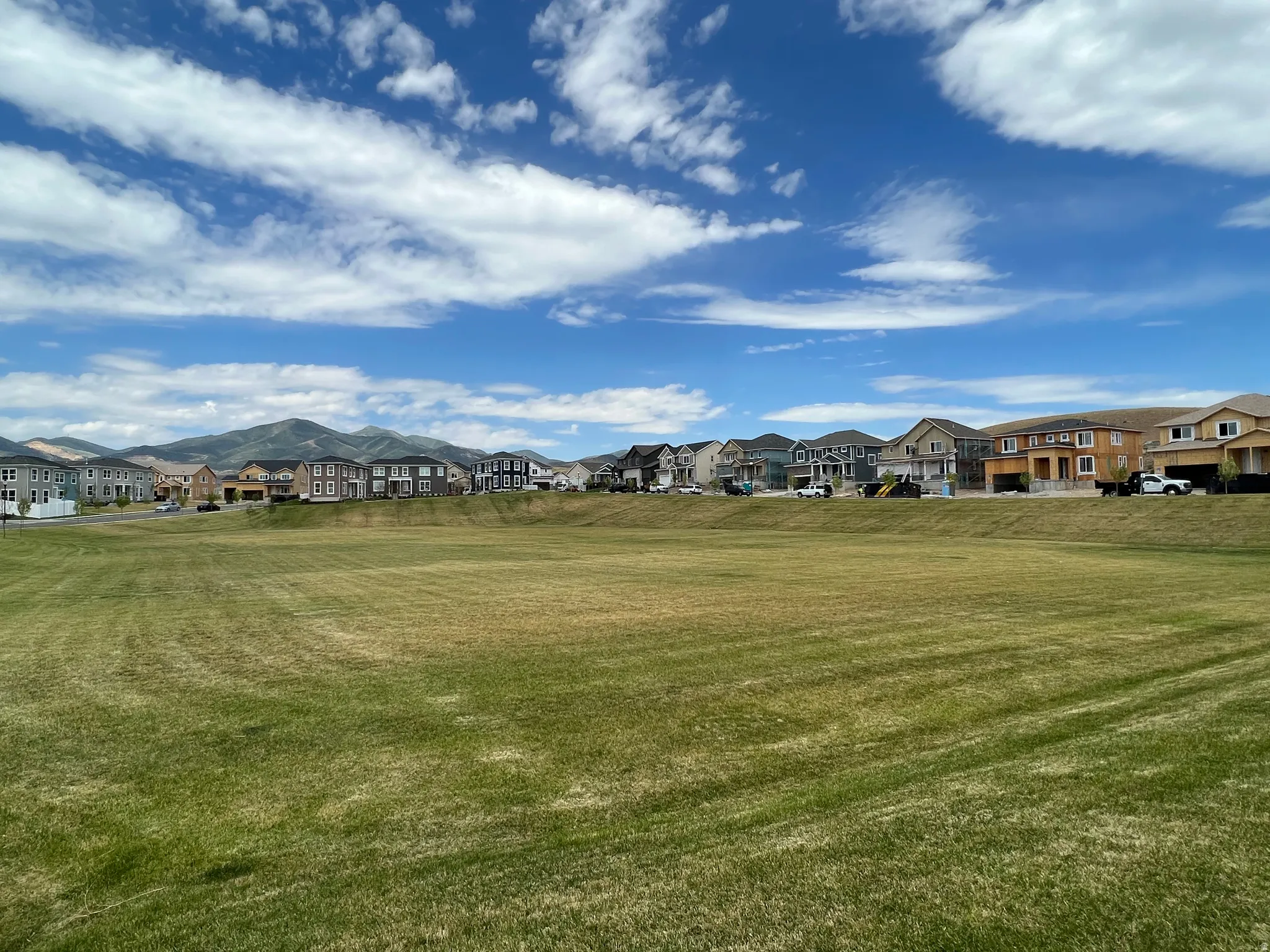 Expansive green space with distant mountain ranges and residential development