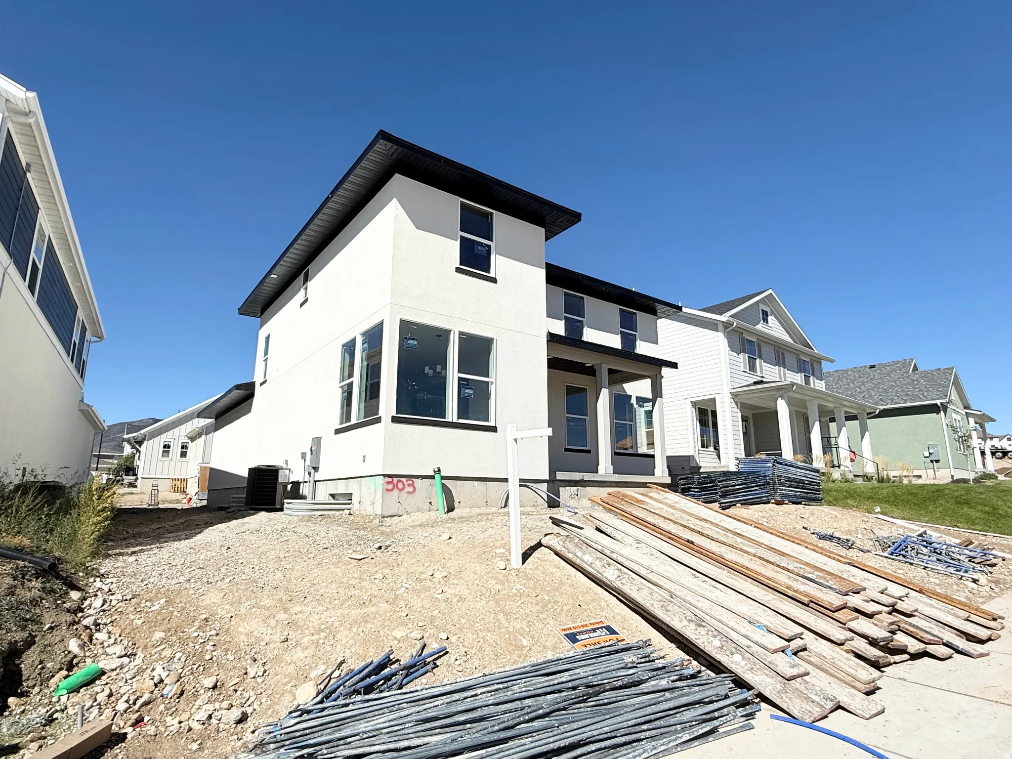 Contemporary exterior with white stucco siding, black trim accents, large windows, and a covered entry