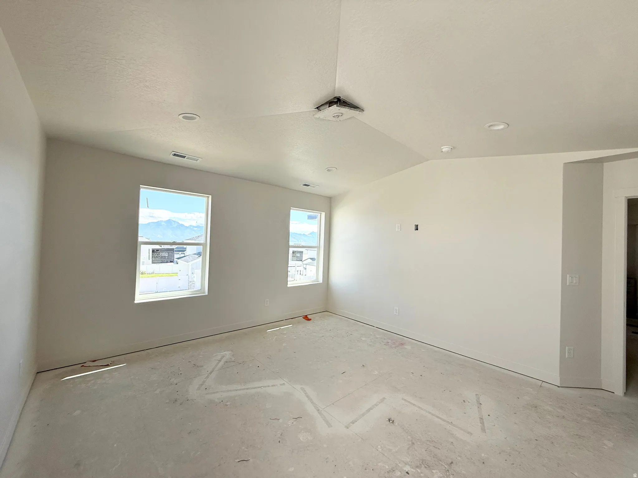 Vaulted ceiling, two windows, recessed lighting, and a white interior