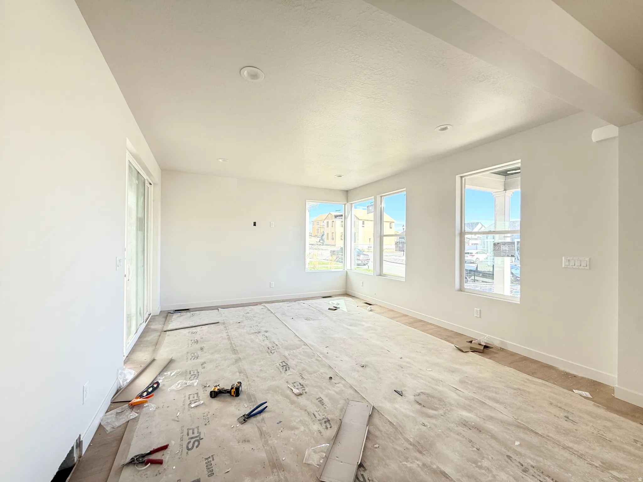 Spacious room featuring multiple windows, a sliding glass door, recessed lighting, and neutral wall tones