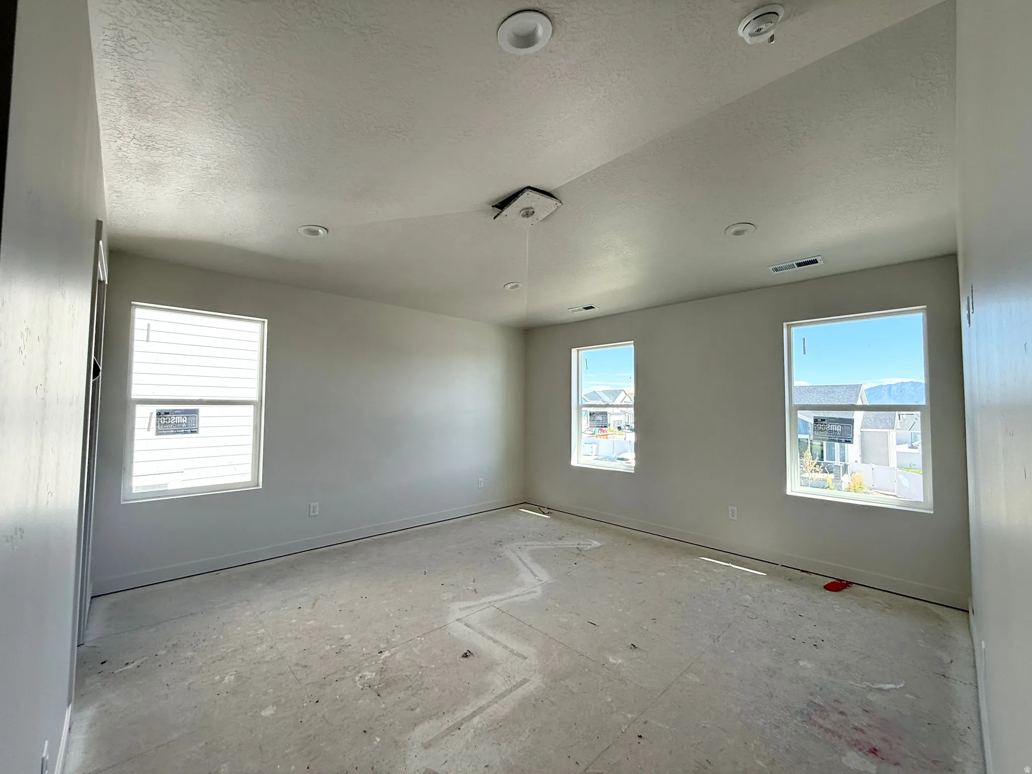 Recessed ceiling lighting, multiple large windows, and neutral wall paint