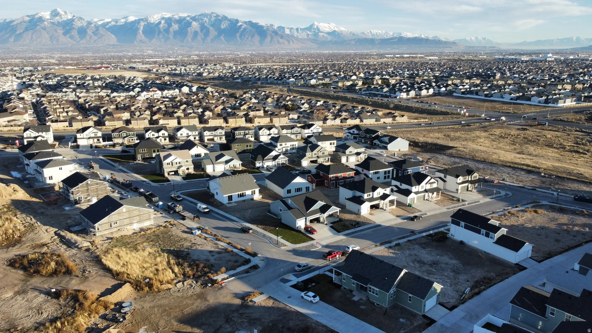 Residential development featuring a variety of single-family homes with gray roofing, concrete driveways, and landscaped front yards