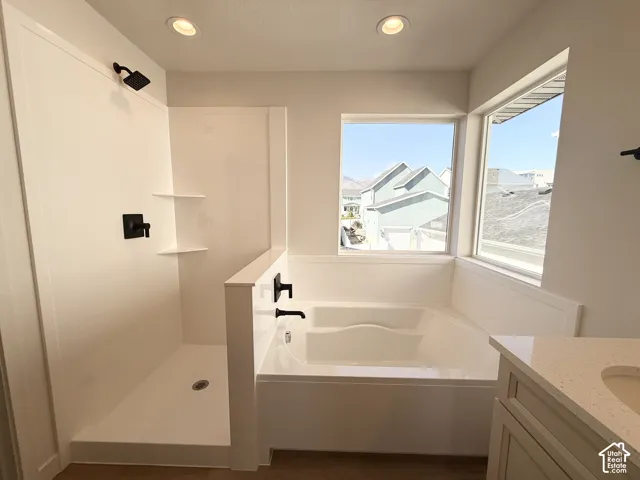 Walk-in shower with matte black fixtures, built-in shower shelves, corner windows, built-in soaking tub, and a vanity with a light-colored countertop