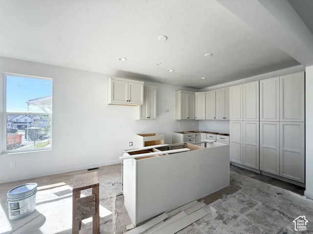 Kitchen area featuring recessed ceiling lighting, light-toned cabinetry, a window, and an island structure