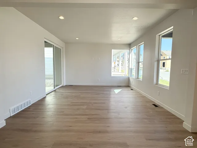 Expansive interior with wood-finish flooring, recessed lighting, multiple large windows, and a sliding glass door