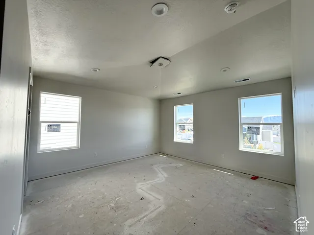 Recessed ceiling lighting, multiple large windows, and neutral wall paint
