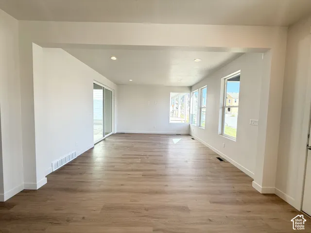 Expansive open-concept living space with wood-finish flooring, recessed lighting, and multiple windows