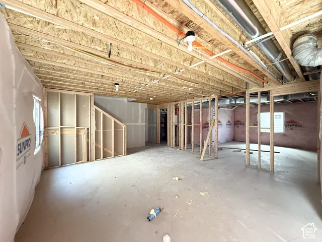 Unfinished lower level featuring exposed wood framing, concrete flooring, and visible utility lines
