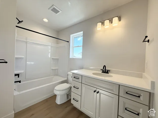 White vanity with integrated sink and chrome hardware, black fixtures, and wood-finish flooring