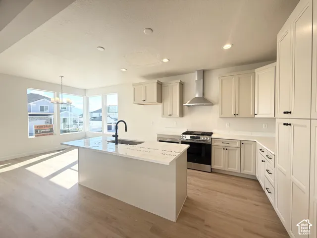 Kitchen featuring a center island with sink, stainless steel appliances, recessed lighting, and wood-finish flooring