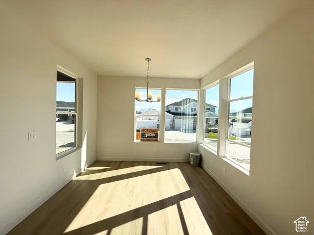 Light wood-finish flooring, multiple large windows, and a hanging light fixture