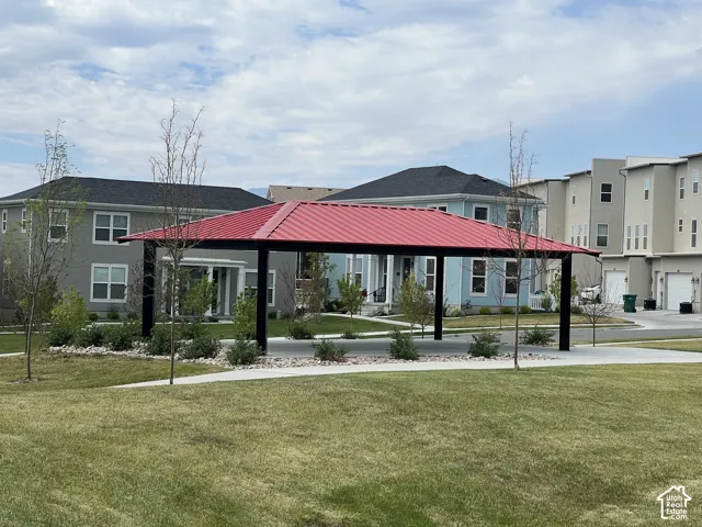 Community pavilion with a red metal roof, surrounded by green lawns and landscaped areas