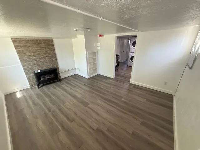 Wood-finish flooring, built-in shelving, stone-tiled accent wall, and a standalone fireplace unit