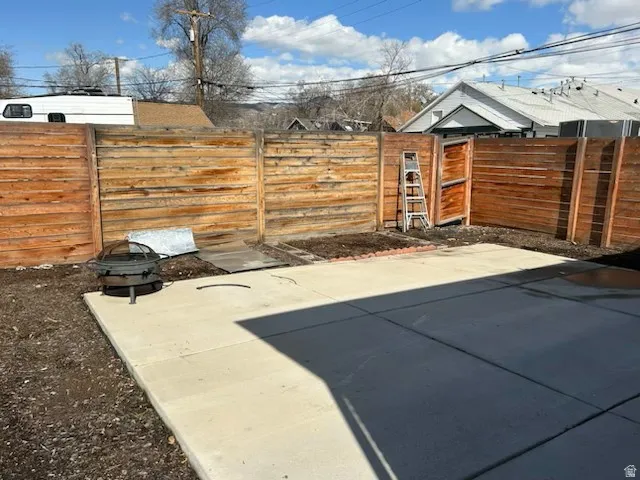 Expansive outdoor patio with concrete paving, wood fencing, and a side access gate