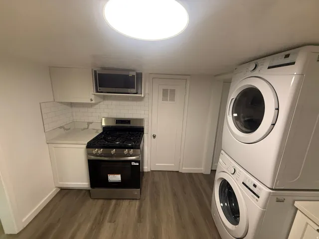 Compact kitchen with white cabinetry, light countertops, white subway tile backsplash, and stainless steel gas range