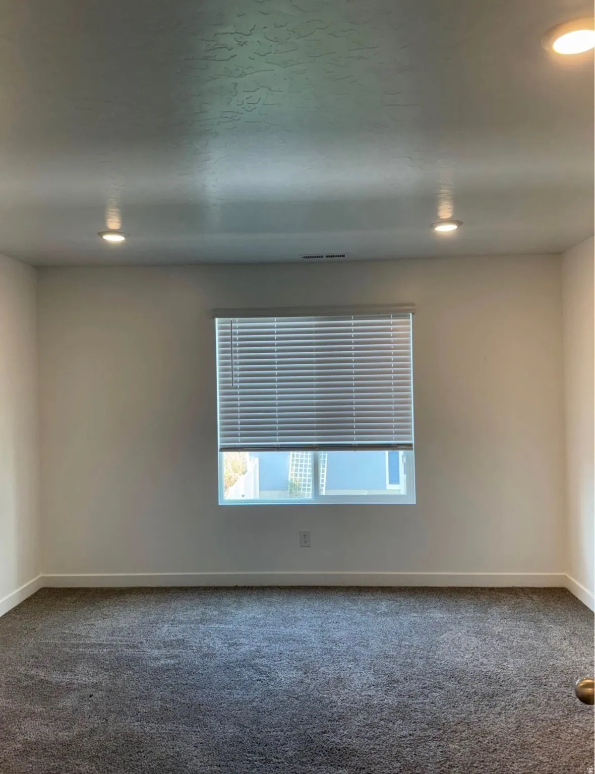 Textured ceiling with recessed lighting, central window with blinds, and wall-to-wall carpeting