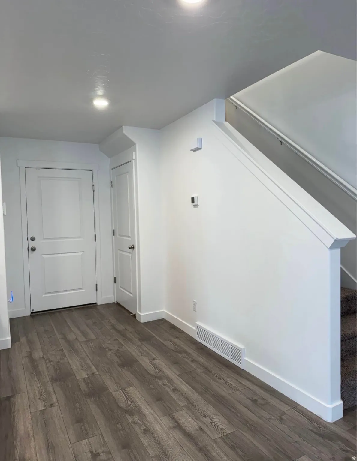 Recessed lighting, wood-finish flooring, white trim, and a carpeted staircase