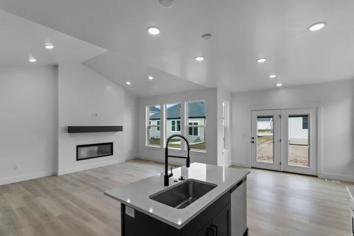 Vaulted ceilings with recessed lighting, linear fireplace with a floating mantel, wood-finish flooring, and double glass-paneled doors