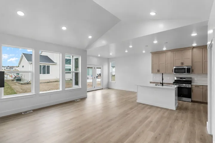 Vaulted ceilings with recessed lighting, large windows, wood-finish flooring, kitchen island, and stainless steel appliances