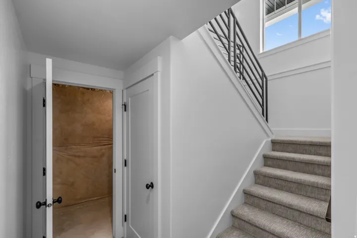 Staircase with carpeted treads, a black metal handrail, and an overhead window