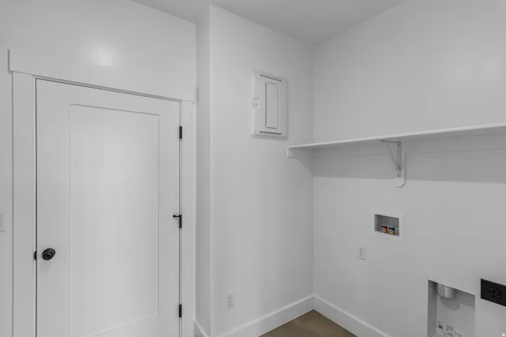 Utility area featuring a built-in shelf, washer/dryer hookups, and a panel door with dark hardware
