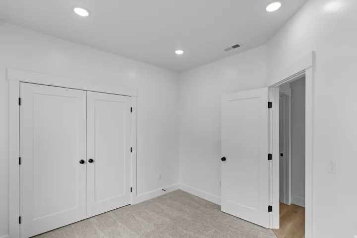 Recessed ceiling lighting, white interior doors, black door hardware, white trim, and light-toned carpeting