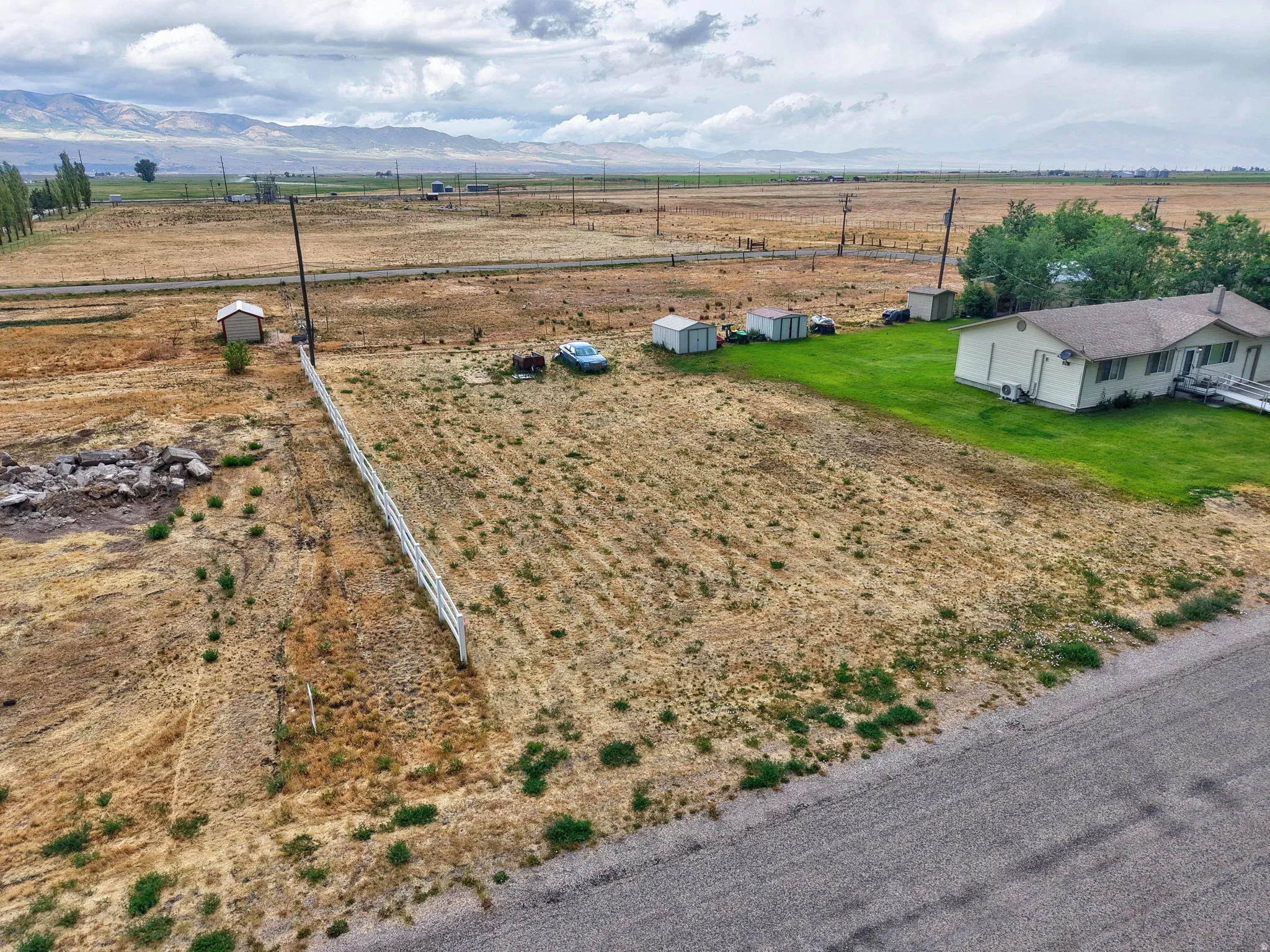 Expansive lot featuring a white fence, detached shed, and distant mountain backdrop