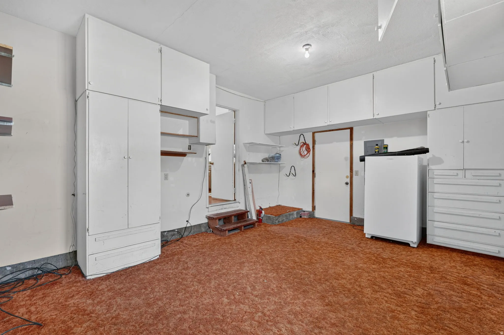 Extensive built-in white cabinetry, additional built-in white storage drawers, and wall-mounted shelving