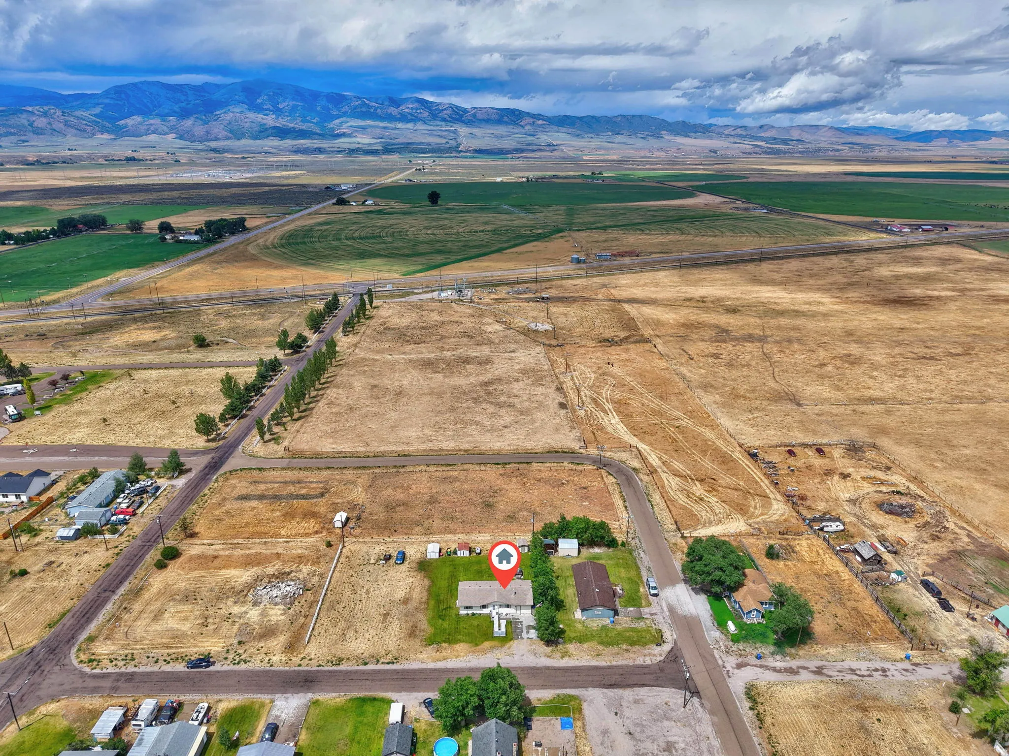 Expansive rural setting with mountain backdrop and surrounding agricultural fields