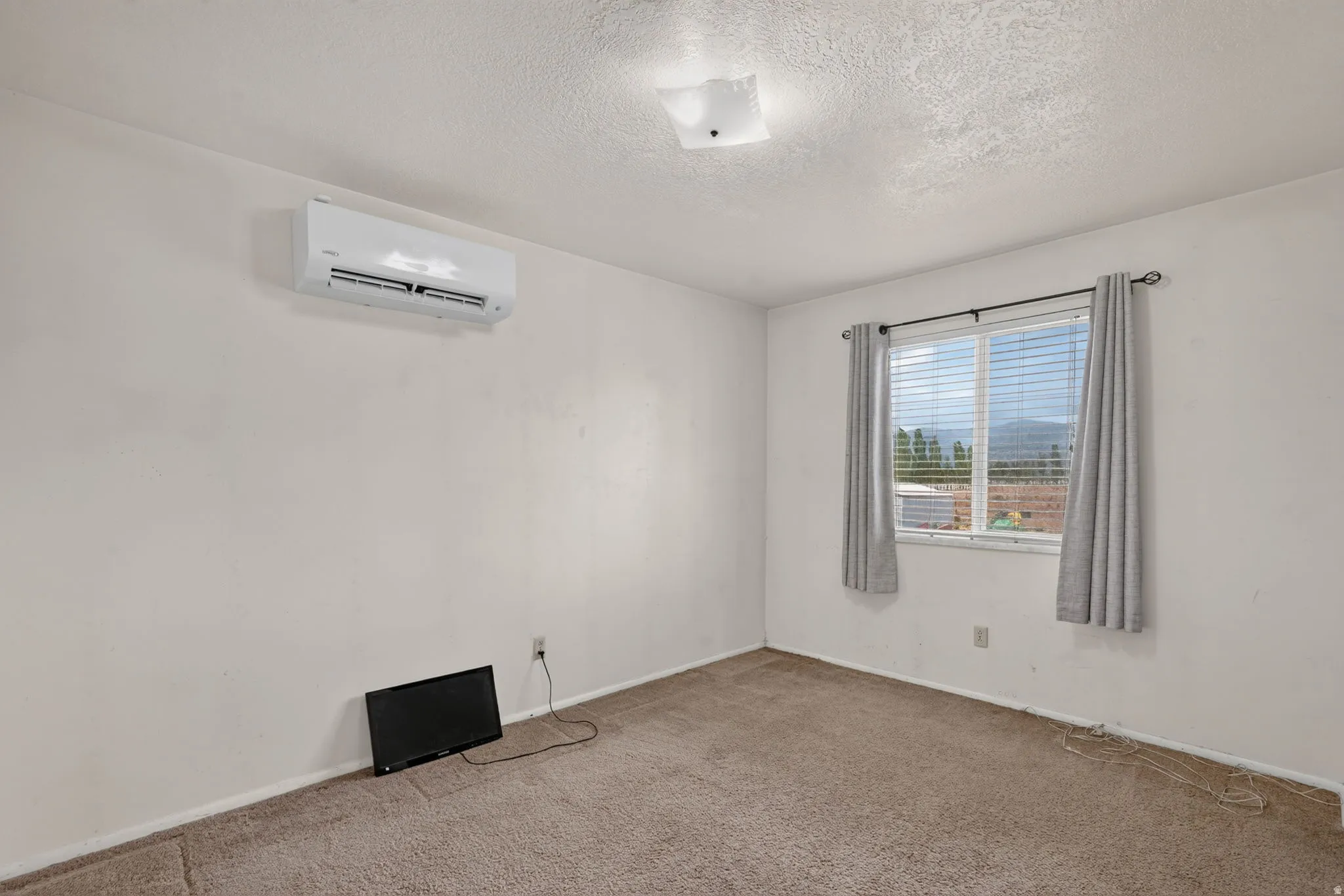 Wall-mounted air conditioning unit, window with blinds and curtains, and ceiling-mounted light fixture