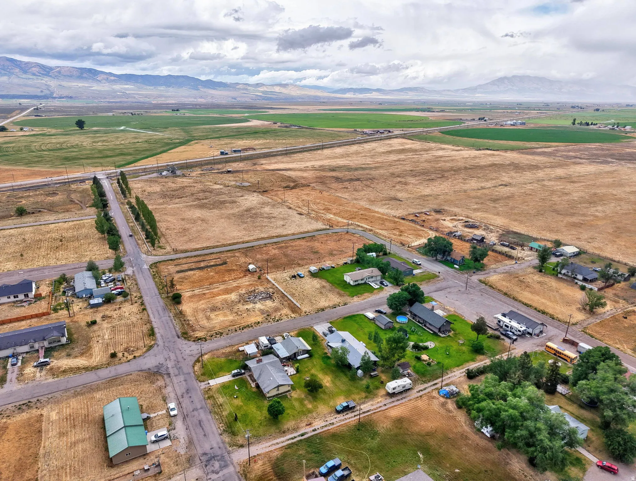 Expansive rural landscape with scattered residential properties, mountain backdrop, and agricultural fields