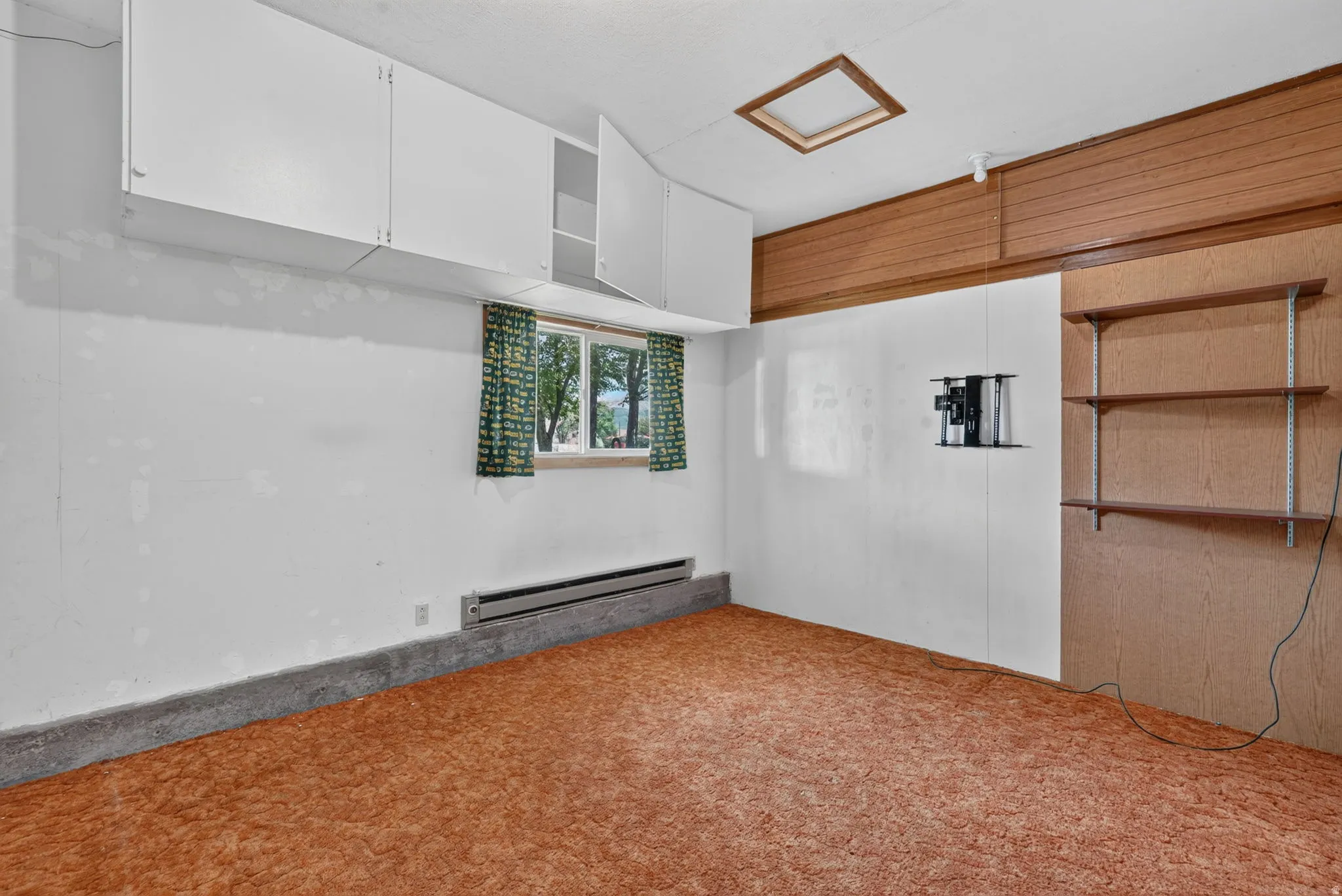 Wall-mounted cabinetry, wall-mounted shelving, wood-finish paneling, and a window with exterior views
