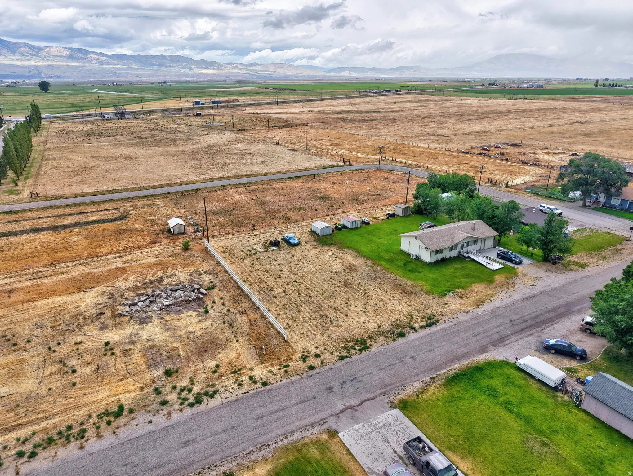 Single-story residence on a lot with green lawn, surrounded by expansive rural land