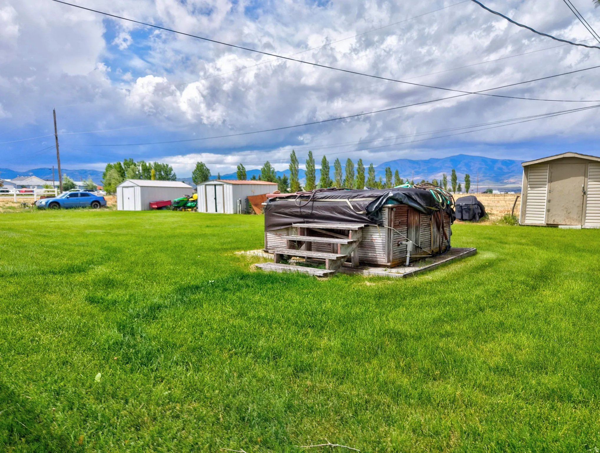 Expansive green lawn with a storage shed and a distant mountain backdrop