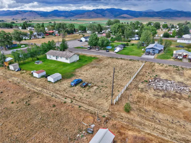 Expansive parcel featuring a white fence, scattered outbuildings, and a mountain backdrop