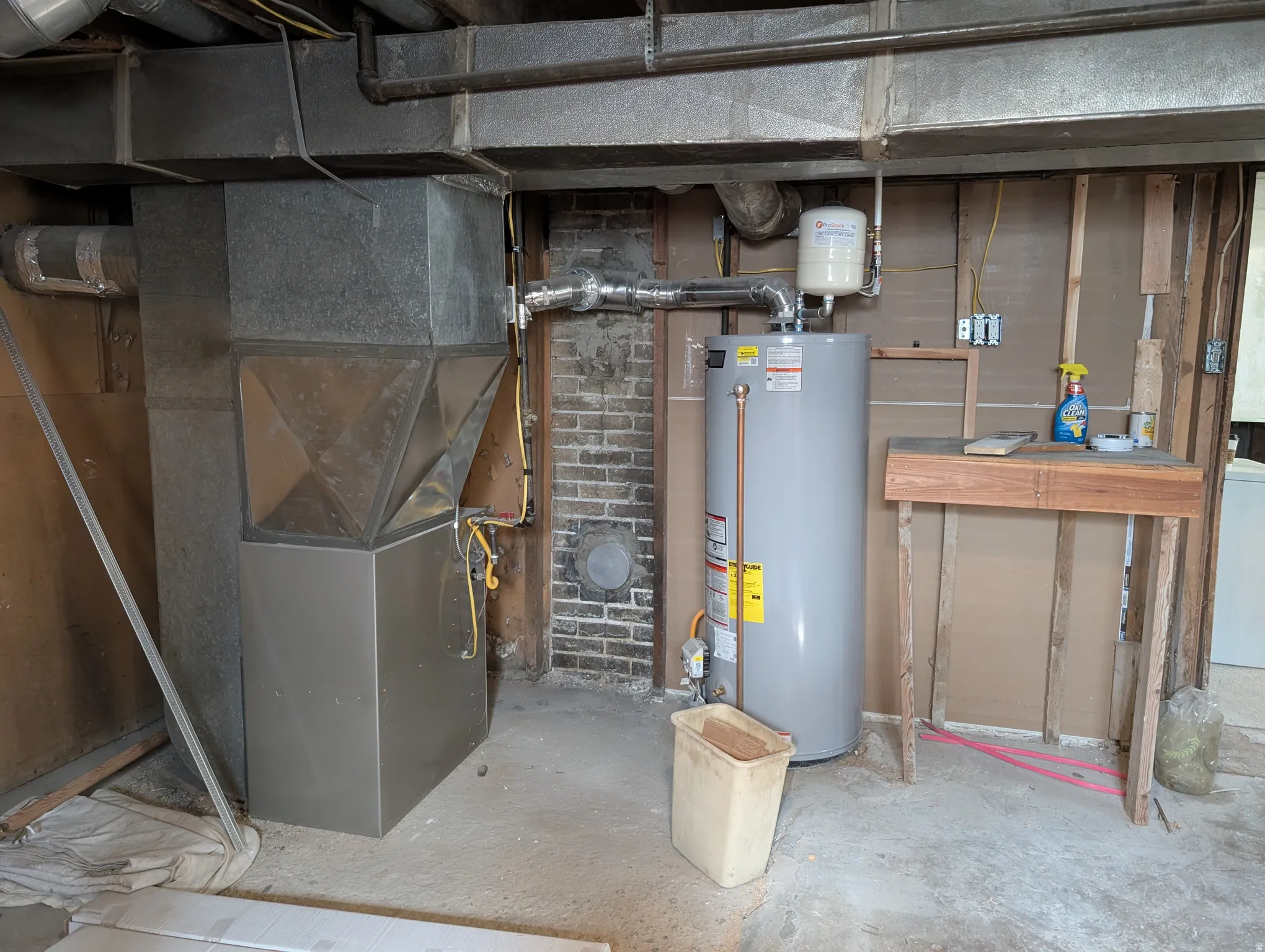 Galvanized ductwork with a water heater and an exposed brick accent wall