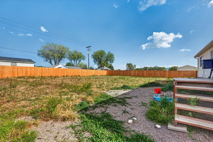 Expansive backyard featuring a new wood privacy fence, gravel patio area, and a wood deck with stairs