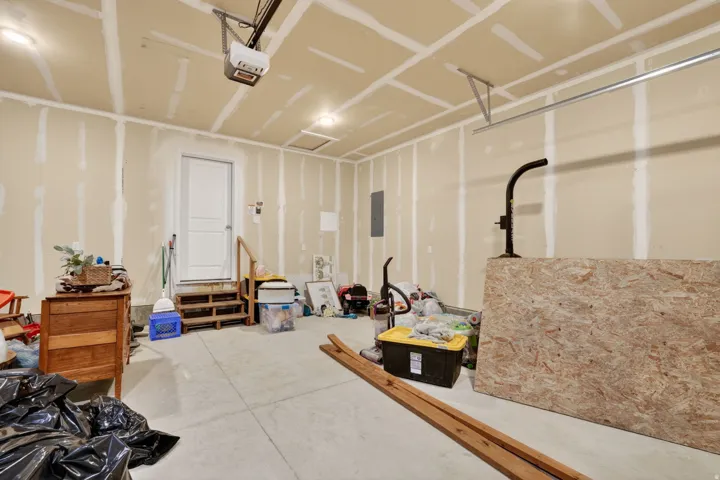 Attached garage with a concrete floor, overhead lighting, and an overhead door opener