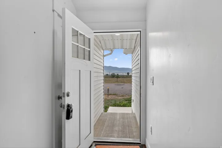 Entryway featuring a panel door with upper window panes, an entryway light fixture, and wood-finish flooring