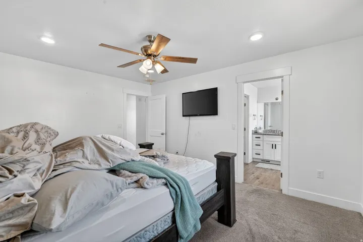 Primary bedroom with ceiling fan and recessed lighting, carpeted flooring, and ensuite bathroom access